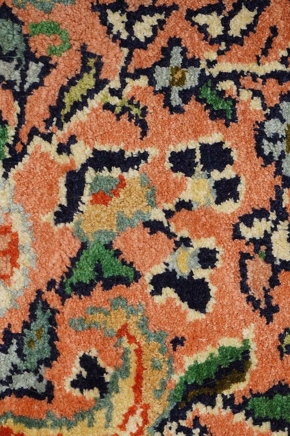 A detailed close-up of the Kirman Persian rug, highlighting its soft, plush texture and intricate floral motifs. The rich peach background contrasts beautifully with navy, green, and ivory accents, showcasing the fine knotting and artistry of traditional Persian weaving.