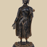 Brass statue of Lord Buddha standing with one hand raised in the Abhaya mudra (gesture of fearlessness and protection), wearing draped robes and standing on a carved lotus base.