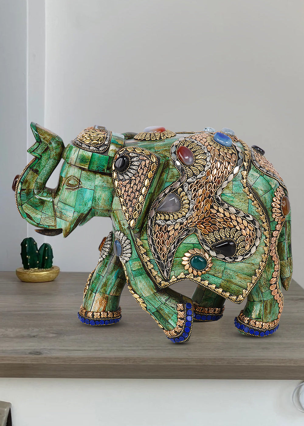Handmade green camel bone elephant sculpture intricately adorned with gold metalwork and colorful gemstone inlays.