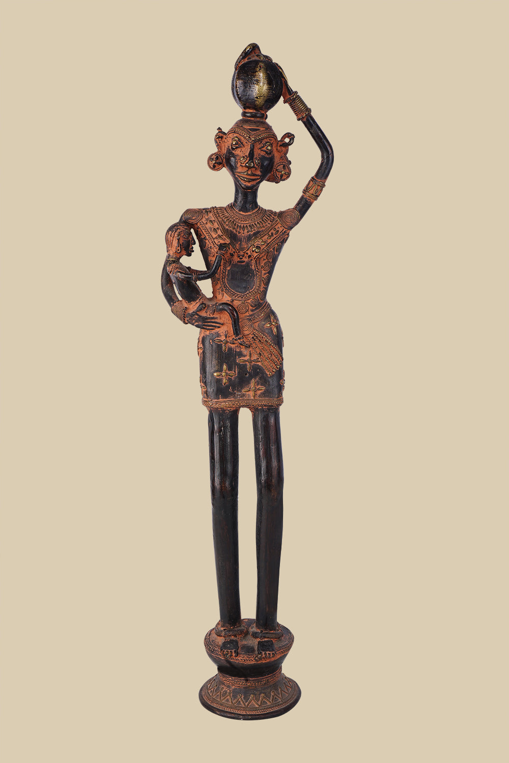 Antique dark brass sculpture of a tribal woman carrying a child in her arms and a pot on her head, adorned with traditional jewelry and standing on a decorated pedestal. The artwork reflects rural life and motherhood.
