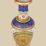 White marble vase with a vibrant hand-painted design featuring intricate floral patterns in rich blues, reds, and greens, accented with gold detailing and small embedded stones. The view is from slightly above, showing the painted interior of the rim.